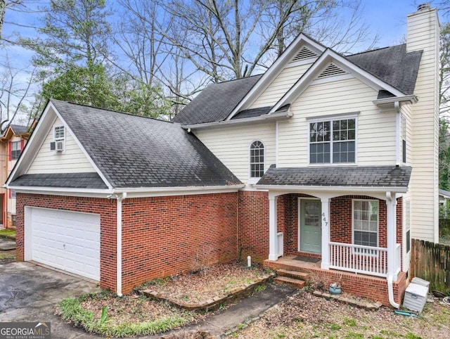 traditional-style home with brick siding, a chimney, a porch, a garage, and driveway