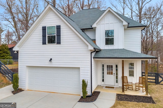 view of front of house featuring a garage, board and batten siding, a shingled roof, and fence