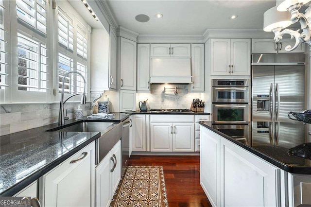 kitchen featuring stainless steel appliances, dark wood-type flooring, a sink, white cabinets, and custom exhaust hood