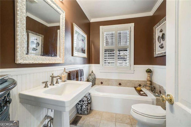 bathroom with wainscoting, toilet, a bath, crown molding, and a sink