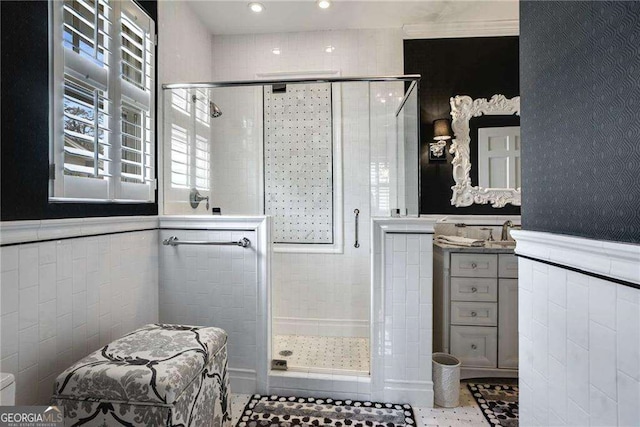 full bath with a stall shower, wainscoting, and tile walls