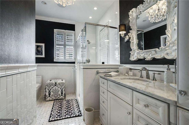 bathroom with tile walls, wainscoting, a shower stall, and vanity