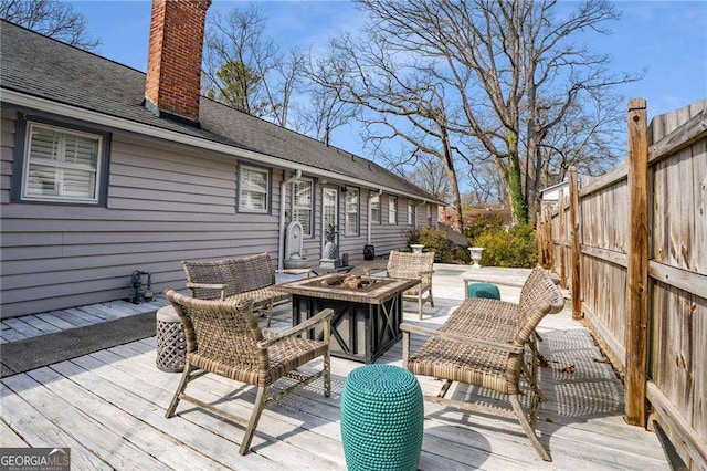 deck featuring an outdoor fire pit and fence