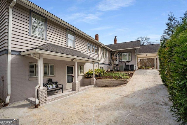 view of front of home with covered porch, concrete driveway, and brick siding