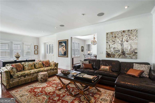 living room with an inviting chandelier, baseboards, ornamental molding, and wood finished floors