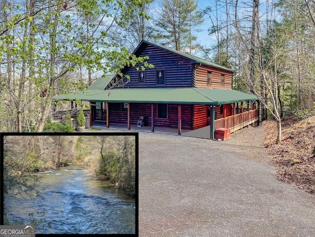 view of front of house featuring a porch, metal roof, and driveway