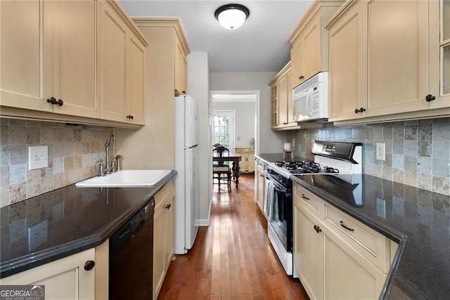 kitchen featuring white appliances, dark wood-style flooring, a sink, and tasteful backsplash