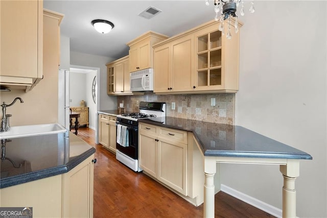 kitchen with visible vents, range with gas stovetop, white microwave, cream cabinets, and a sink