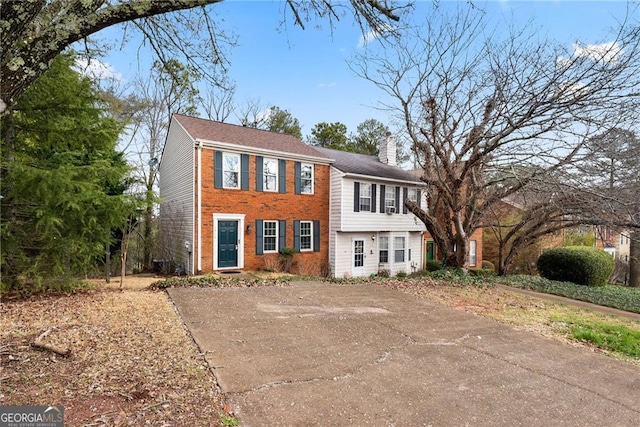 view of front facade with a chimney and brick siding