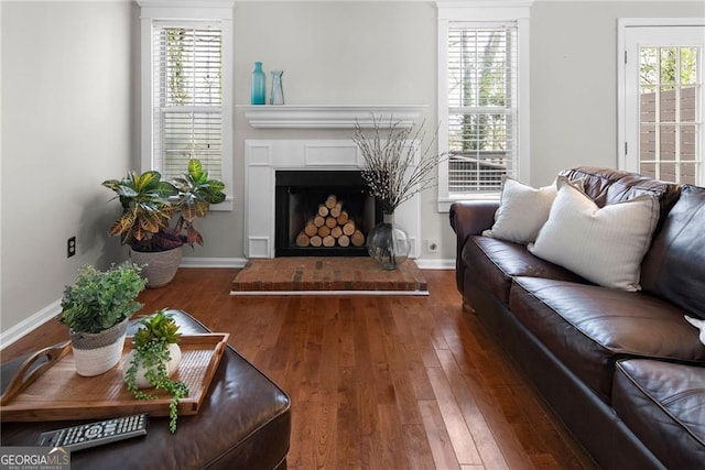 living room with a wealth of natural light, a fireplace with raised hearth, and hardwood / wood-style floors
