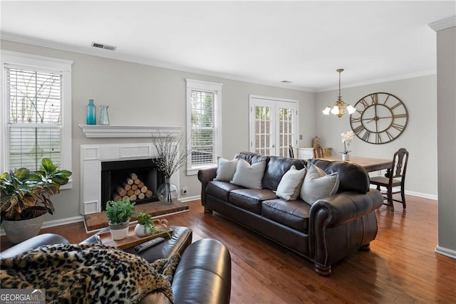 living room featuring a chandelier, dark wood-type flooring, ornamental molding, and visible vents