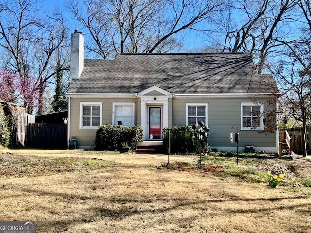 view of front of house featuring a chimney, a front lawn, and roof with shingles