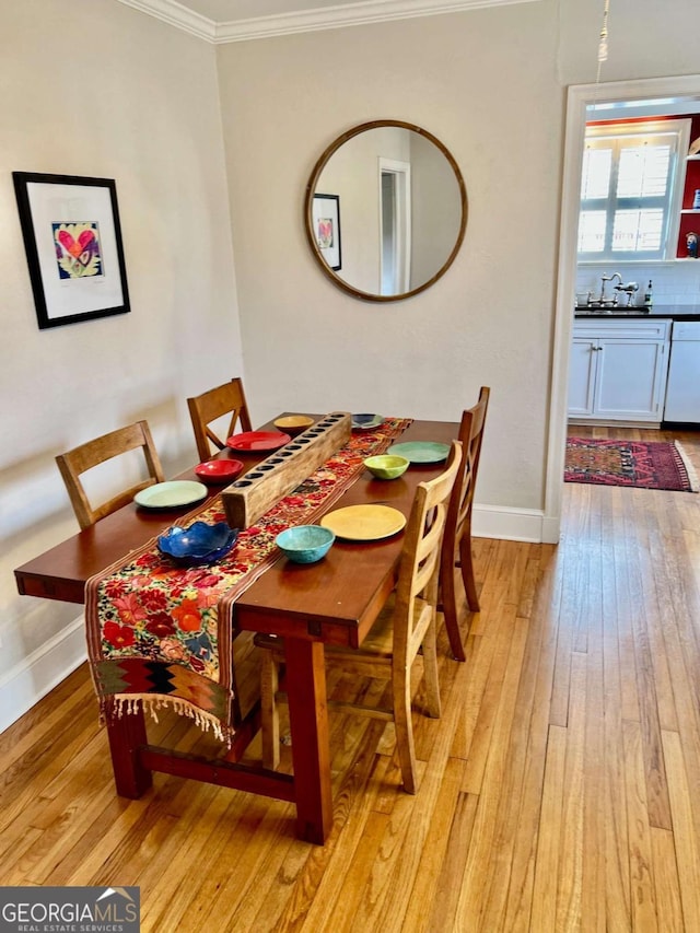 dining area with baseboards, light wood-style flooring, and crown molding