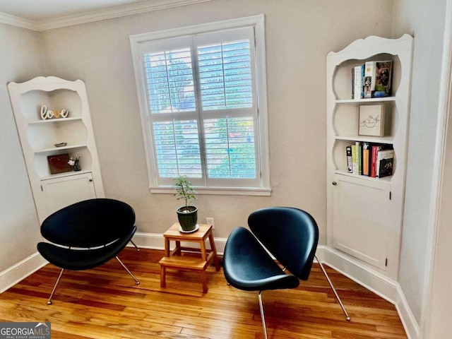 sitting room featuring baseboards, ornamental molding, and wood finished floors