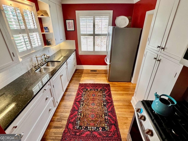 kitchen featuring open shelves, stainless steel appliances, white cabinets, a sink, and light wood-type flooring