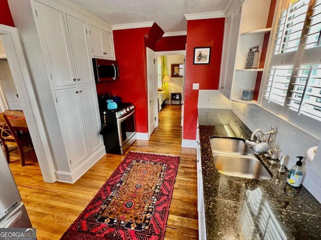 kitchen featuring light wood finished floors, white cabinetry, appliances with stainless steel finishes, and a sink