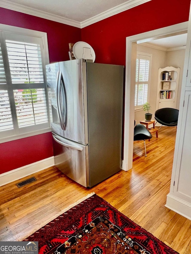 kitchen with baseboards, visible vents, crown molding, light wood-style floors, and stainless steel refrigerator with ice dispenser