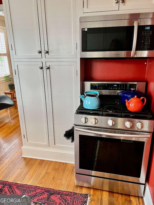 kitchen with stainless steel appliances, light wood-type flooring, and white cabinets