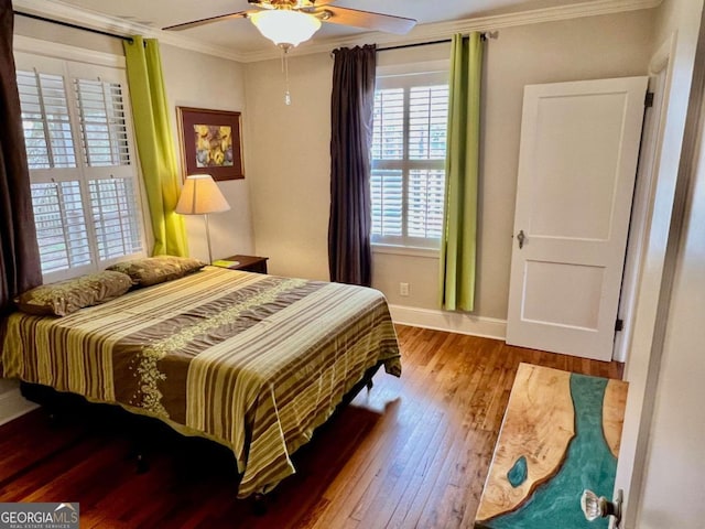 bedroom featuring ornamental molding, wood-type flooring, a ceiling fan, and baseboards