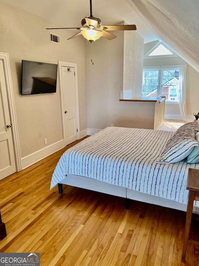 bedroom with lofted ceiling, baseboards, visible vents, and light wood finished floors