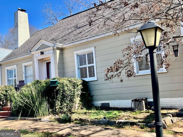 view of front of home featuring crawl space, a shingled roof, and a chimney