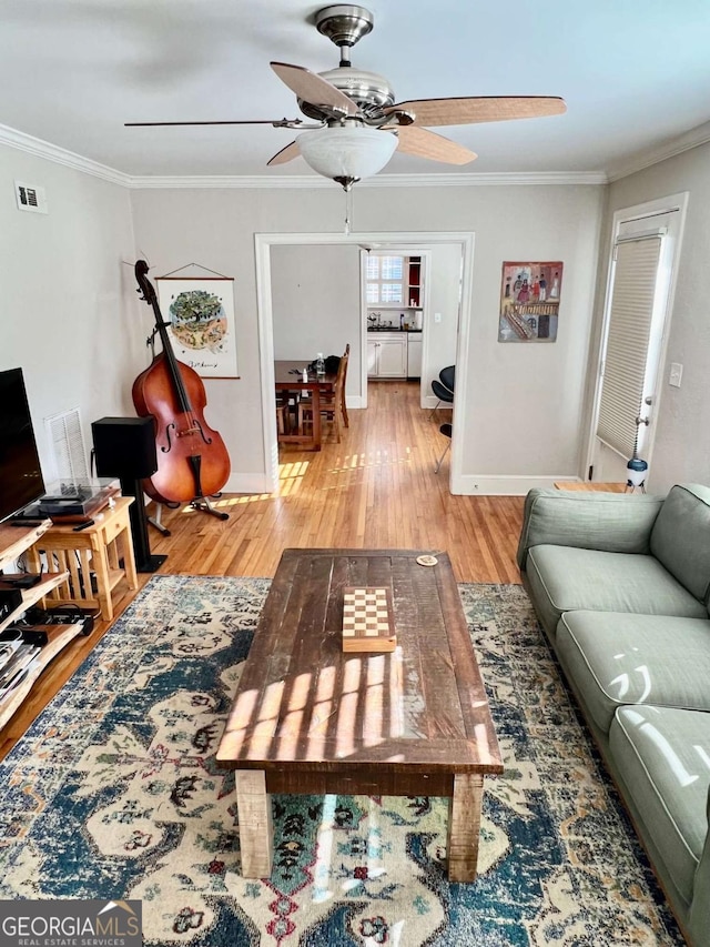 living room featuring visible vents, ornamental molding, and wood finished floors