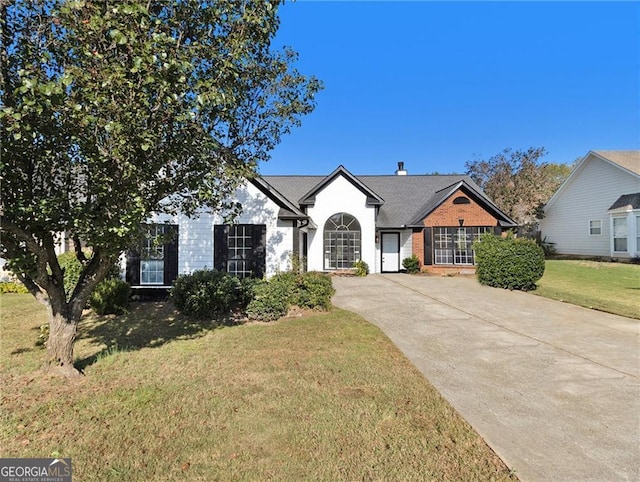 view of front facade with concrete driveway, brick siding, a chimney, and a front yard