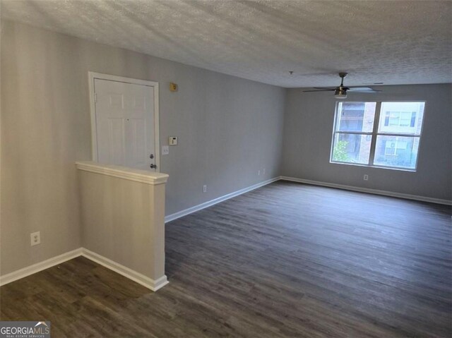 spare room featuring dark wood-style flooring, ceiling fan, a textured ceiling, and baseboards