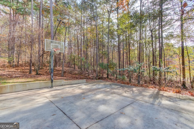 view of basketball court featuring a wooded view and basketball court