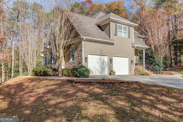 view of property exterior featuring a garage, stone siding, driveway, and a shingled roof