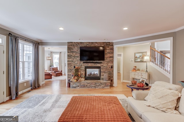 living room featuring baseboards, light wood-style flooring, a stone fireplace, stairs, and crown molding