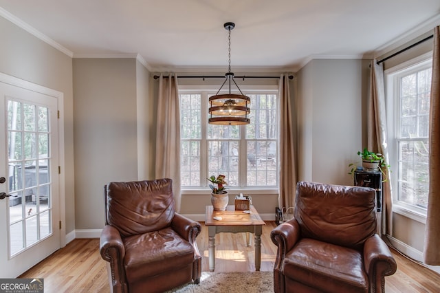 sitting room with an inviting chandelier, light wood-style flooring, baseboards, and ornamental molding