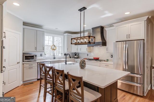 kitchen featuring premium range hood, stainless steel appliances, light wood-style flooring, and a sink