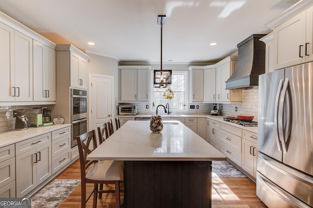 kitchen with premium range hood, a kitchen island, a breakfast bar, stainless steel appliances, and light wood-type flooring