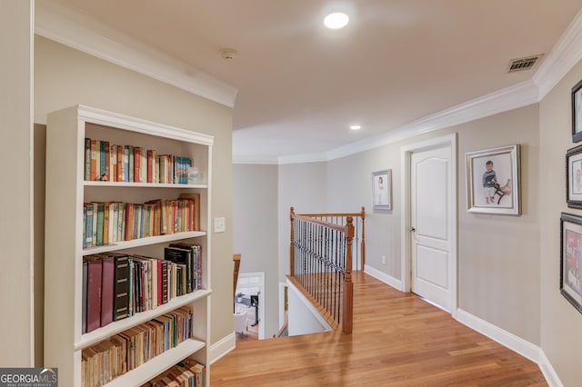 corridor with visible vents, crown molding, baseboards, an upstairs landing, and wood finished floors