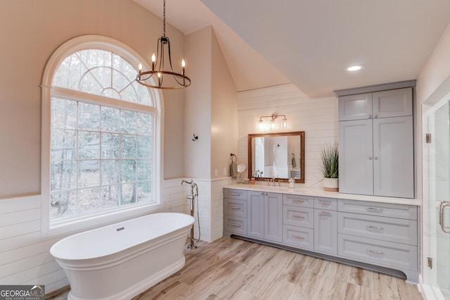 full bathroom with a wainscoted wall, a stall shower, wood finished floors, a freestanding bath, and vanity