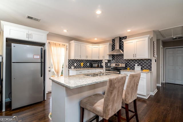 kitchen featuring visible vents, dark wood finished floors, white cabinetry, appliances with stainless steel finishes, and wall chimney range hood