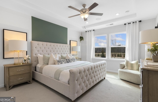 bedroom featuring baseboards, a raised ceiling, visible vents, and light colored carpet