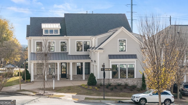 modern farmhouse with a shingled roof, a standing seam roof, brick siding, and metal roof