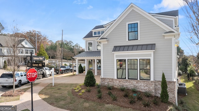 view of front of house featuring metal roof, brick siding, and a standing seam roof