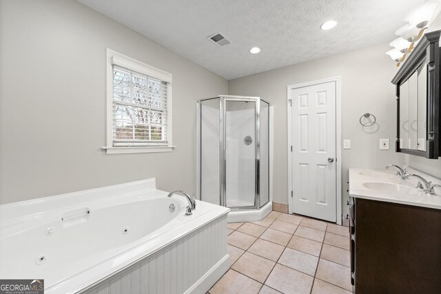 bathroom with double vanity, a stall shower, a sink, a textured ceiling, and tile patterned flooring