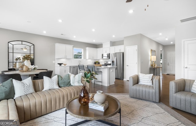 living area with light wood-type flooring, visible vents, ceiling fan, and recessed lighting