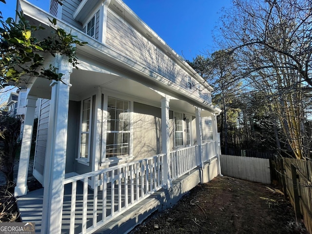 view of home's exterior with covered porch and fence