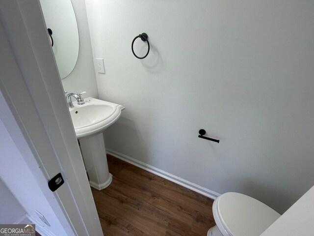 bathroom with a sink, toilet, baseboards, and wood finished floors