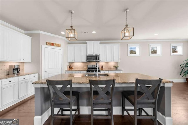 kitchen featuring appliances with stainless steel finishes, white cabinets, dark wood finished floors, and a breakfast bar area