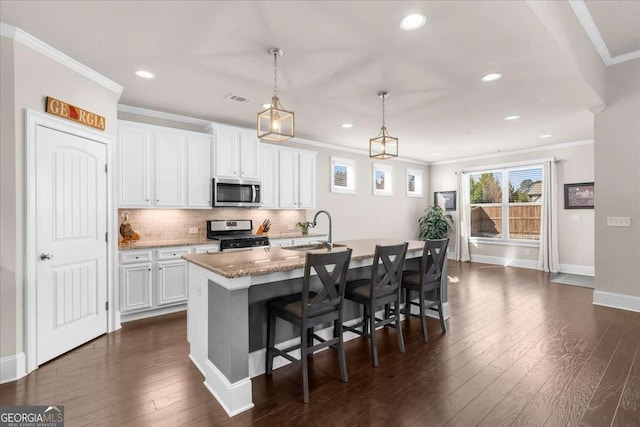 kitchen featuring a kitchen island with sink, stainless steel appliances, dark wood-style flooring, a sink, and crown molding