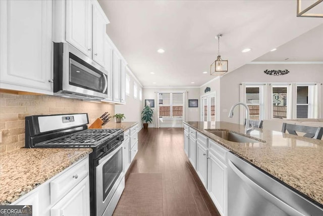 kitchen with backsplash, appliances with stainless steel finishes, dark wood-type flooring, ornamental molding, and a sink