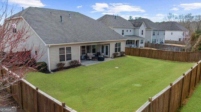 rear view of property featuring a patio area, a yard, and a fenced backyard