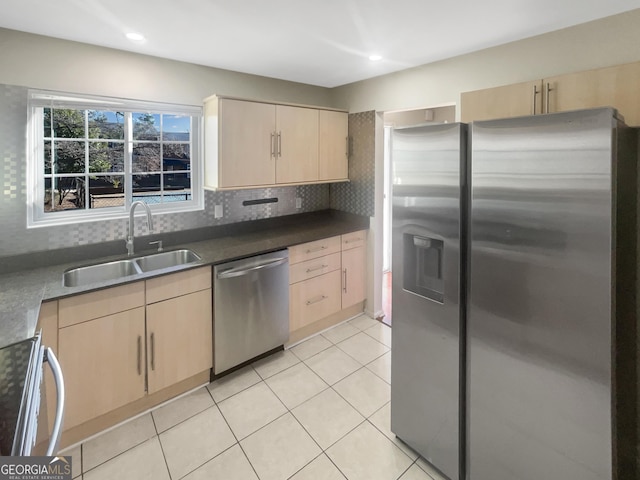 kitchen featuring light brown cabinets, stainless steel appliances, a sink, and light tile patterned flooring