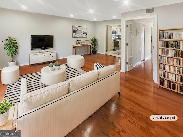 living room with baseboards, wood finished floors, visible vents, and recessed lighting